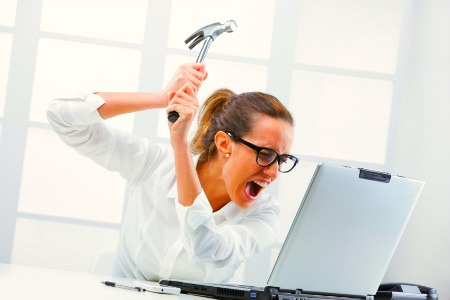 Freaked out business woman with a hammer ready to smash her laptop computer